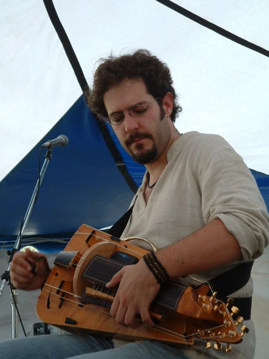 a man playing the violin in front of a blue tent
