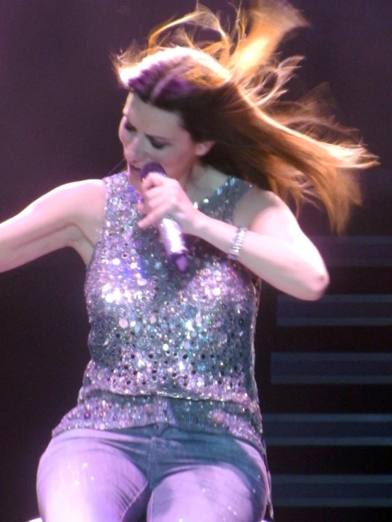 the woman is on stage holding her hair in the wind