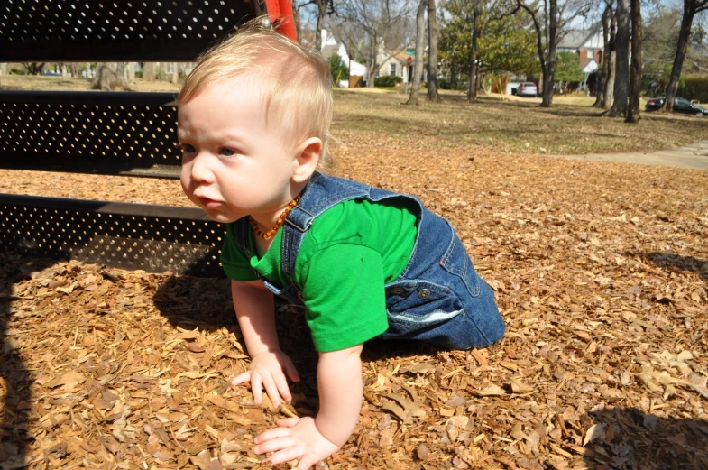 a small boy crawling down the side of a wooden bench
