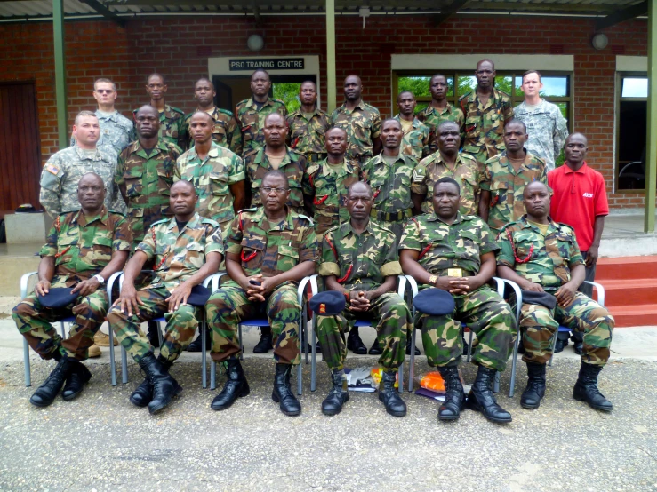 several military officers sitting on chairs with their arms around each other