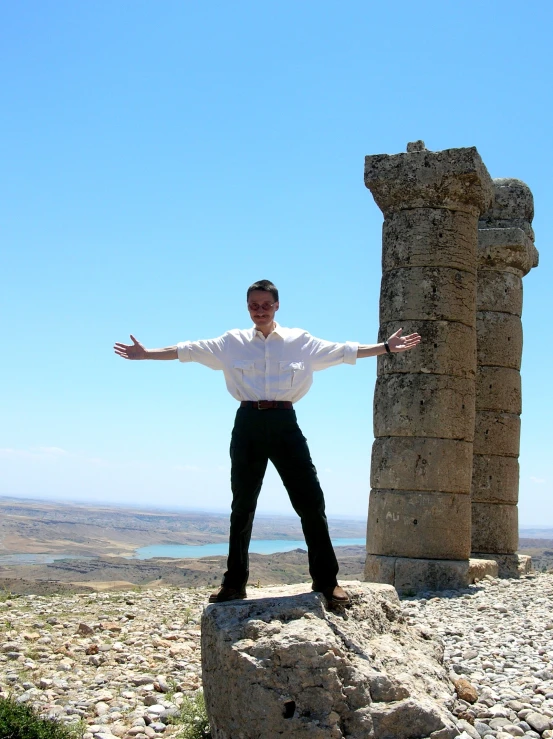 man standing in front of a stone pillar