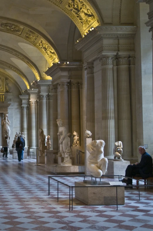 a view of a hall with statues on a checkered floor