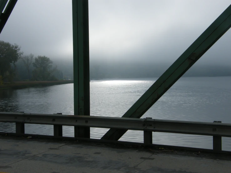 a person sitting on a bridge looking over the water