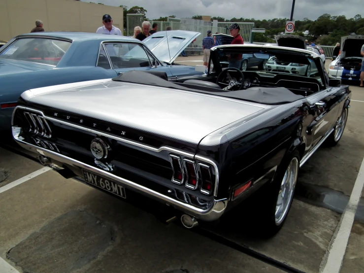 an old black car sitting in a parking lot