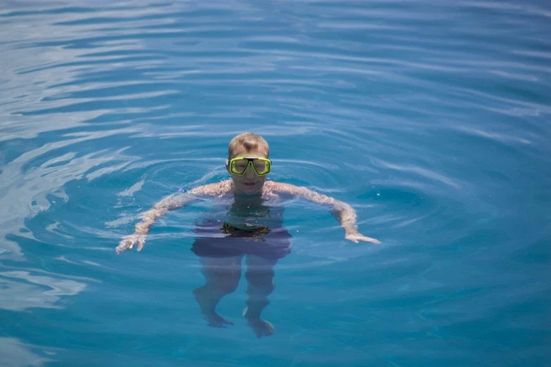 a man swimming through the blue water wearing goggles