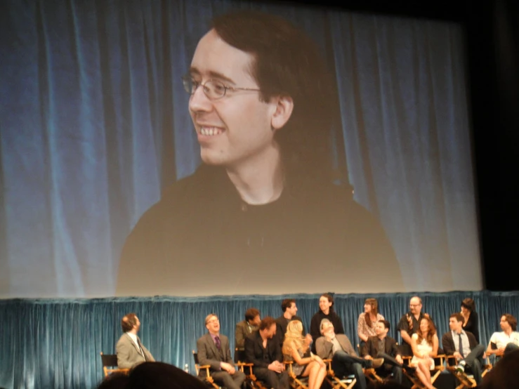 several people are sitting on stage during a movie