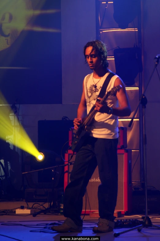 a male guitarist in a white shirt is playing his guitar