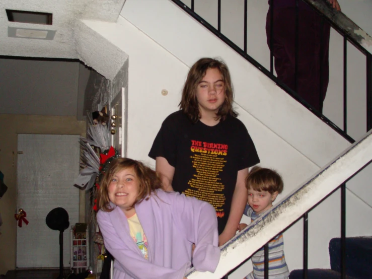 two children in purple and one is standing on the stairs