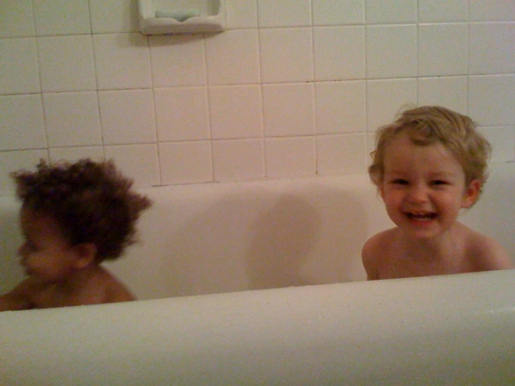 two young children playing in a bathtub