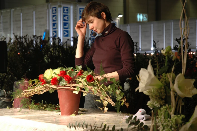 a woman in a red sweater standing by a flower arrangement