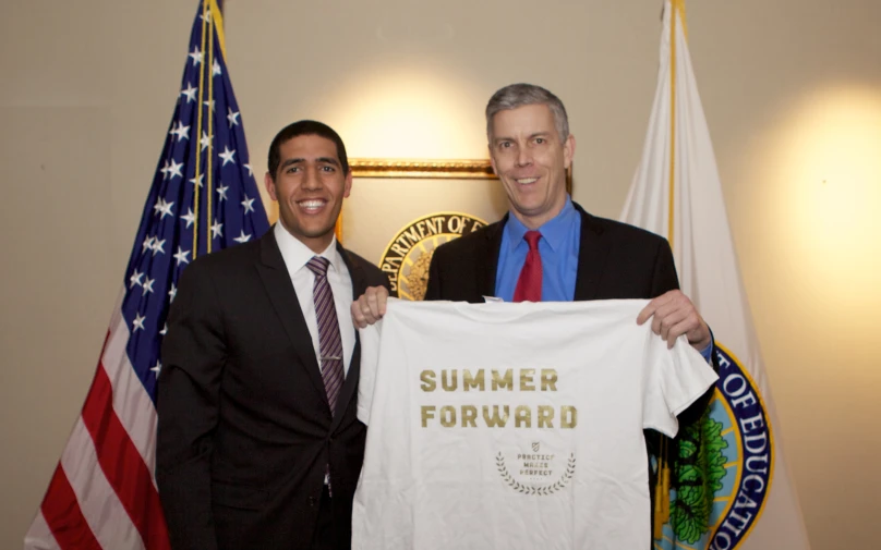 two men holding an award t - shirt while posing with flags