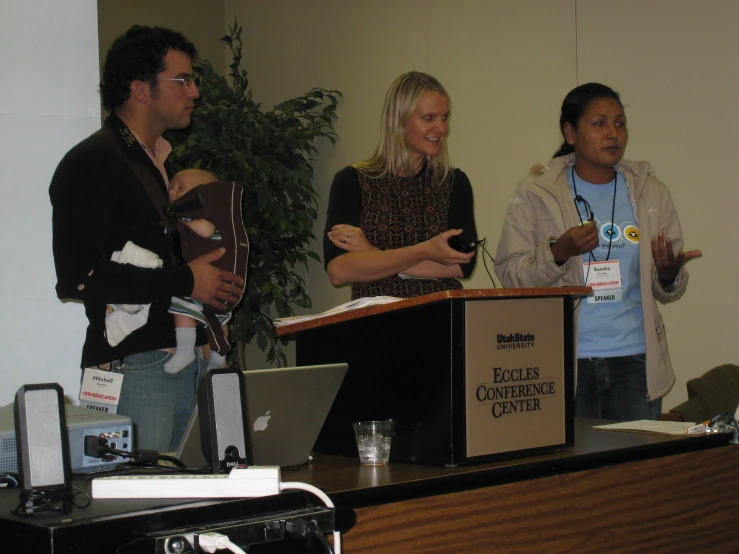 people in front of a podium with two men and one woman