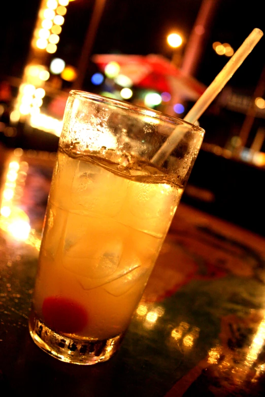 a glass filled with drink sitting on top of a table