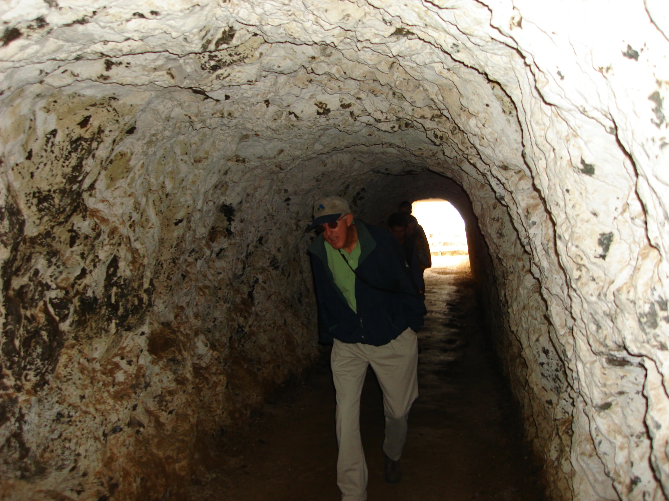 a man walking down a narrow path with a cell phone in his hand