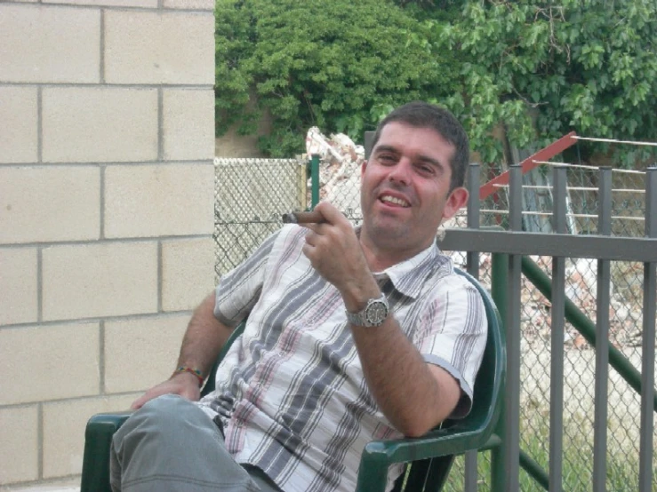 the man sits in a chair holding a small object
