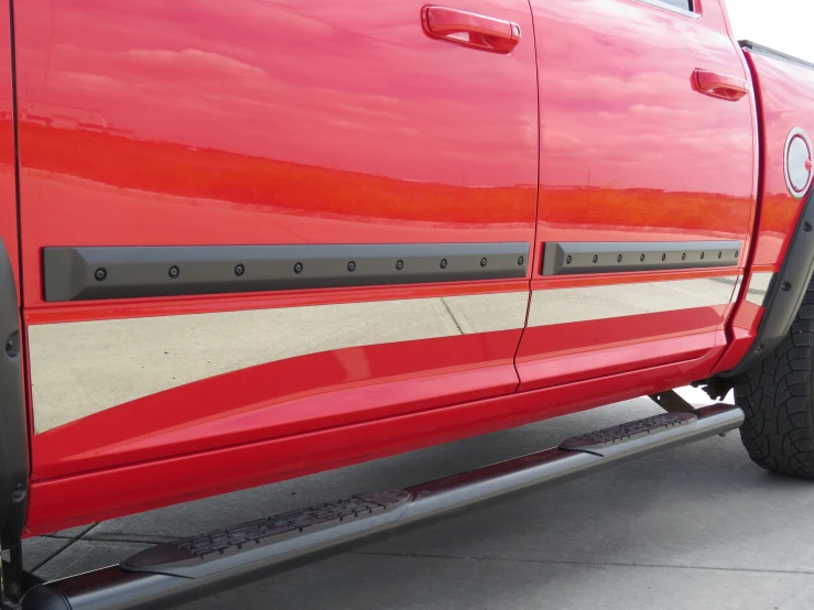 a red truck parked near a curb with some water