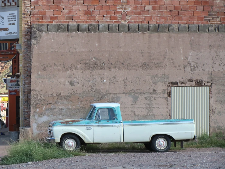 a blue truck in front of a faded red brick wall