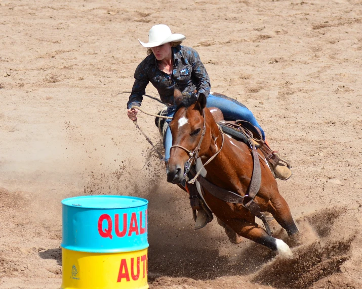 a woman in cowboy clothes on a horse in an arena