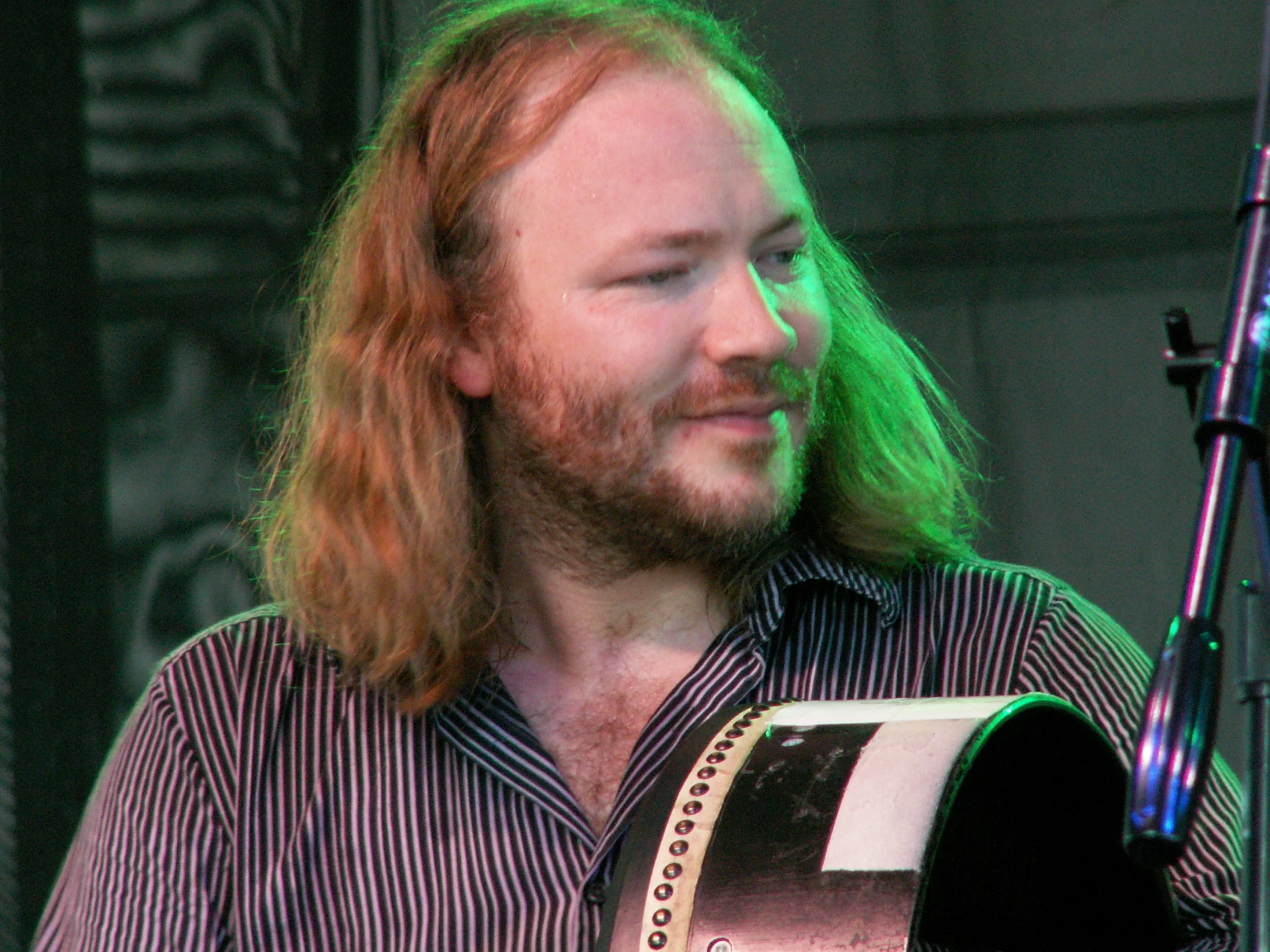 a man with long hair in front of a microphone