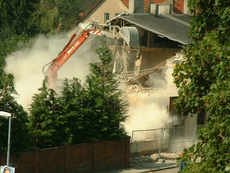 an excavator is clearing down a house from its demolition
