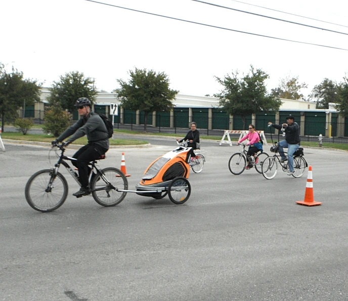 four people riding bicycles on street between cones