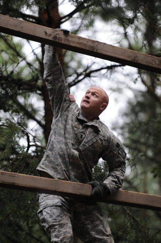 a man in camouflage clothing standing on a rail next to trees