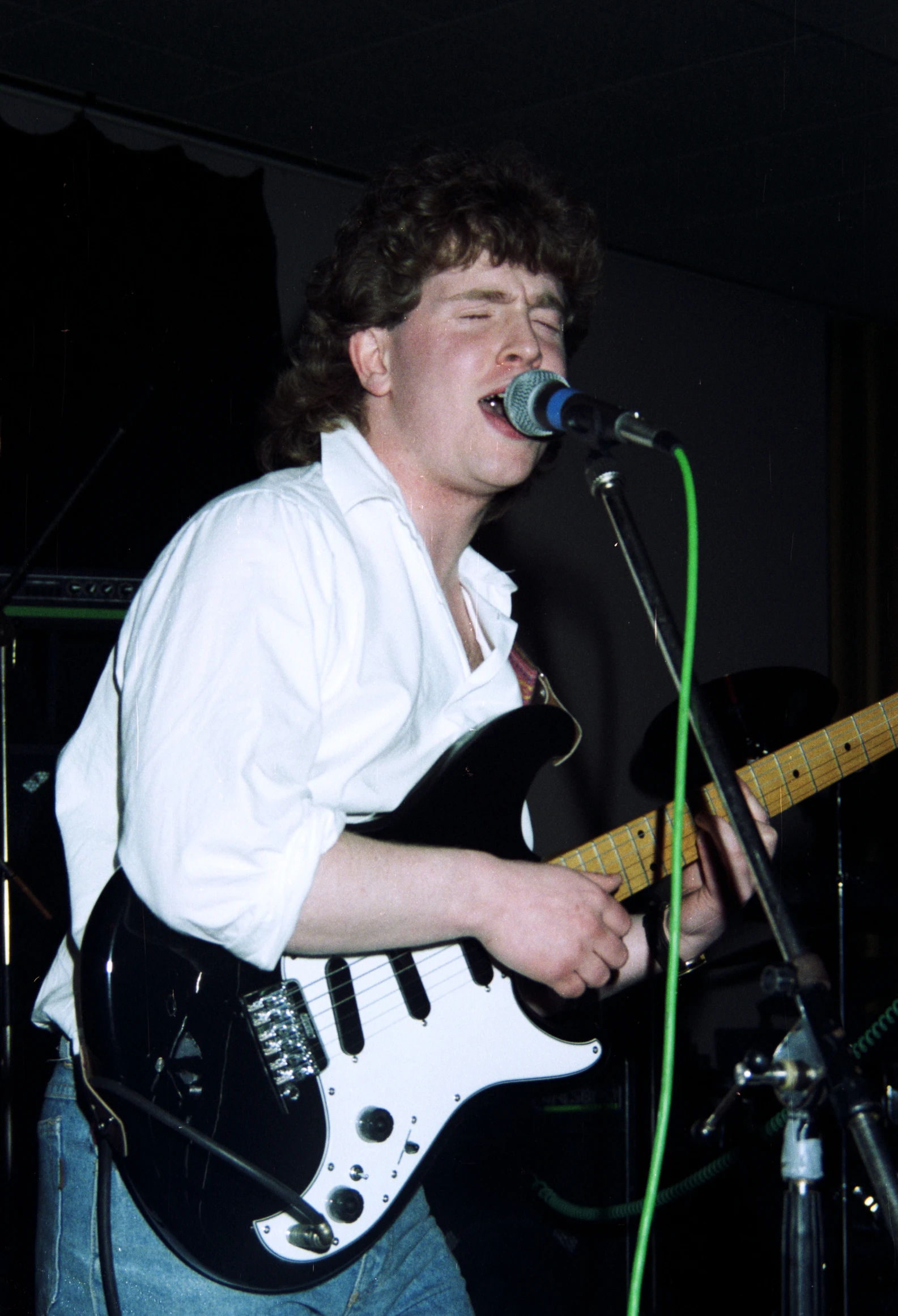 a man singing into a microphone while holding an electric guitar