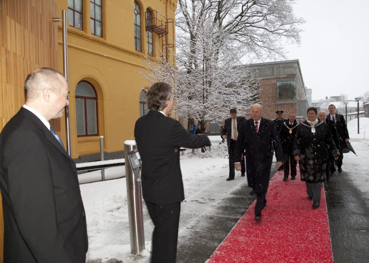 a red carpet and two people in black suits are on a red carpeted sidewalk