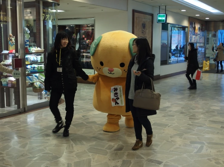two women standing next to a big stuffed bear