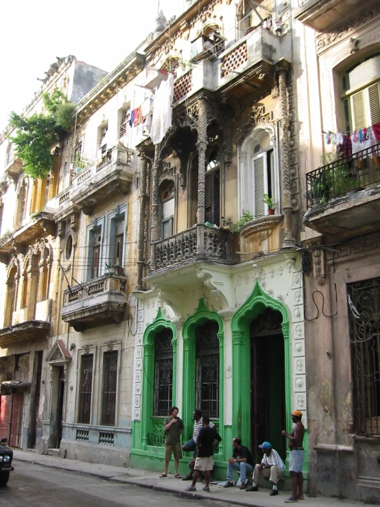 a group of people walking on the sidewalk in front of an old building