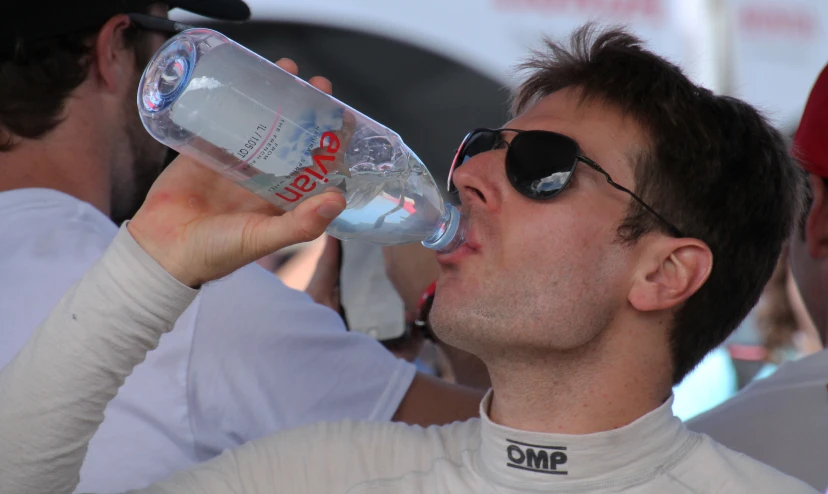 a man wearing sun glasses drinks water from a bottle