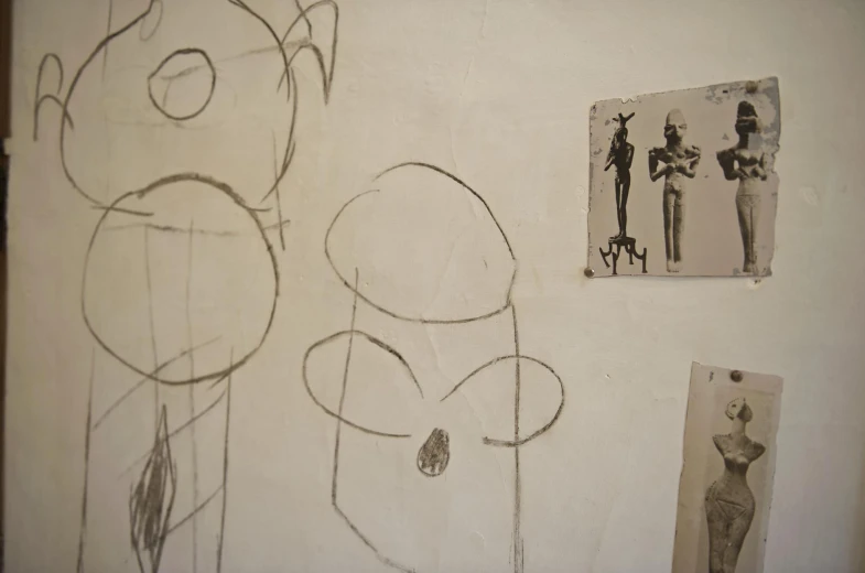 three pictures on the wall, with one drawing of people