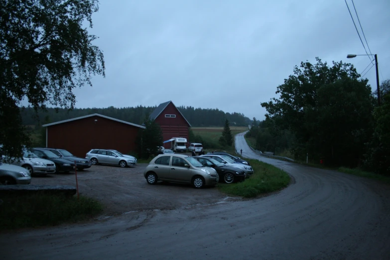 cars parked in a driveway outside an old barn