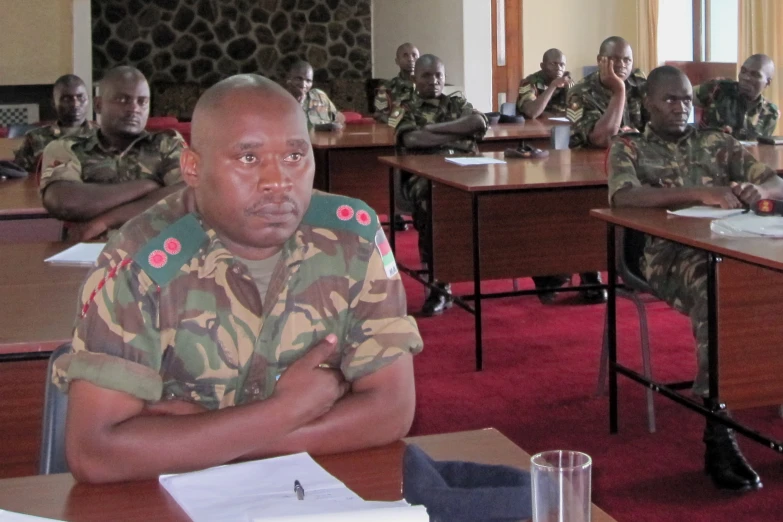 army soldiers sitting in a room while wearing uniforms