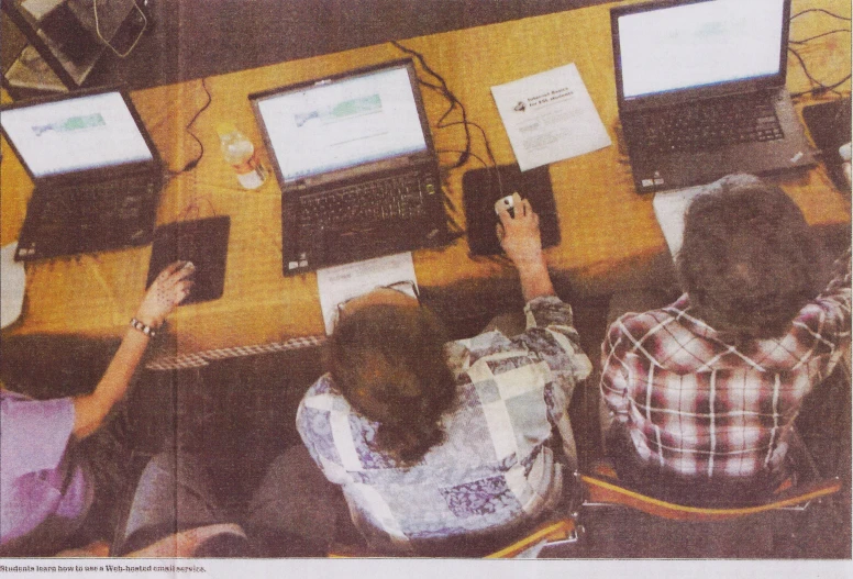 group of people sitting at tables in front of monitors