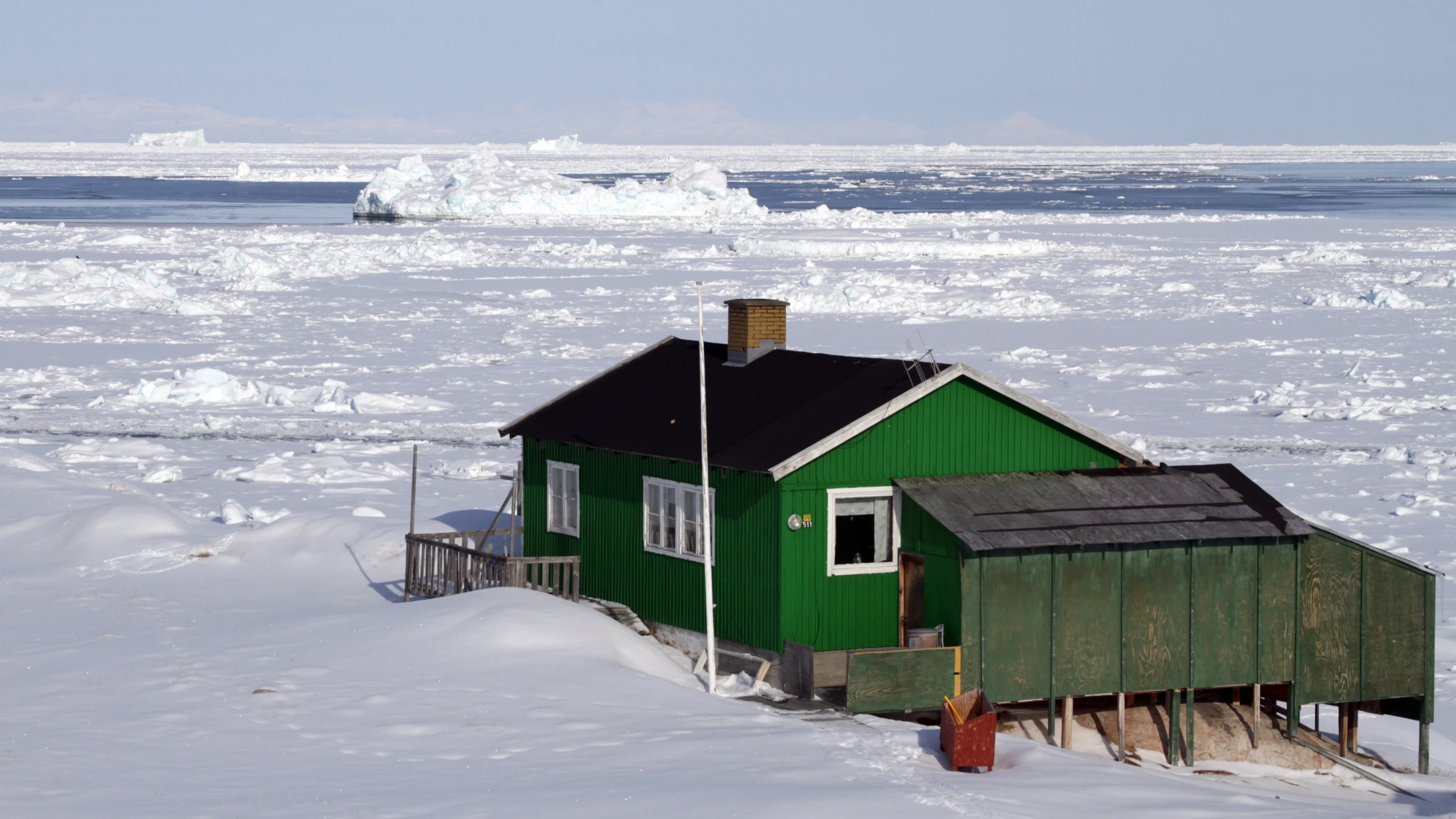 a small green cottage is surrounded by snow and ice