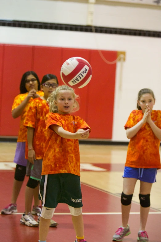 the girls in orange shirts are playing volleyball