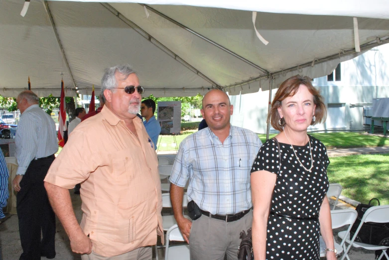 several people standing under a canopy, in a park