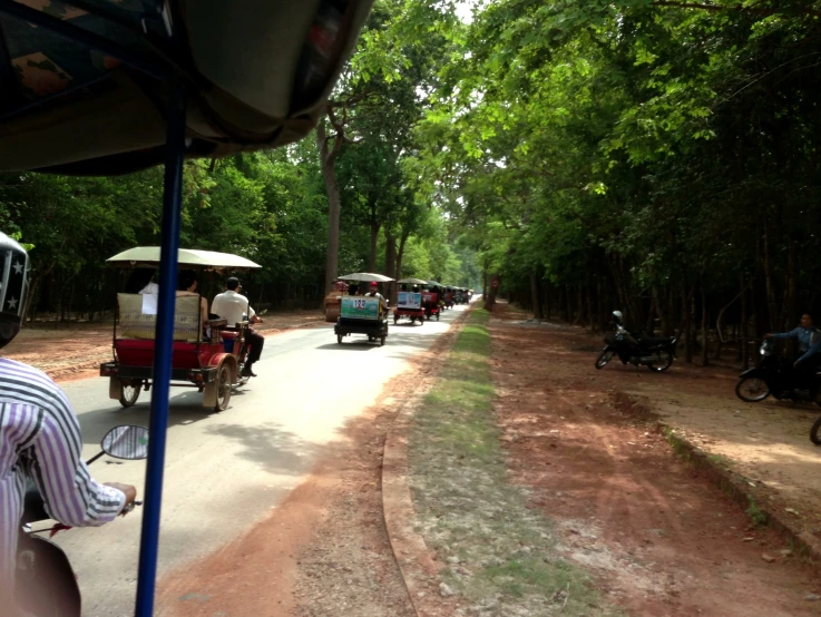three wheeled rickshaws are driving down a dirt road