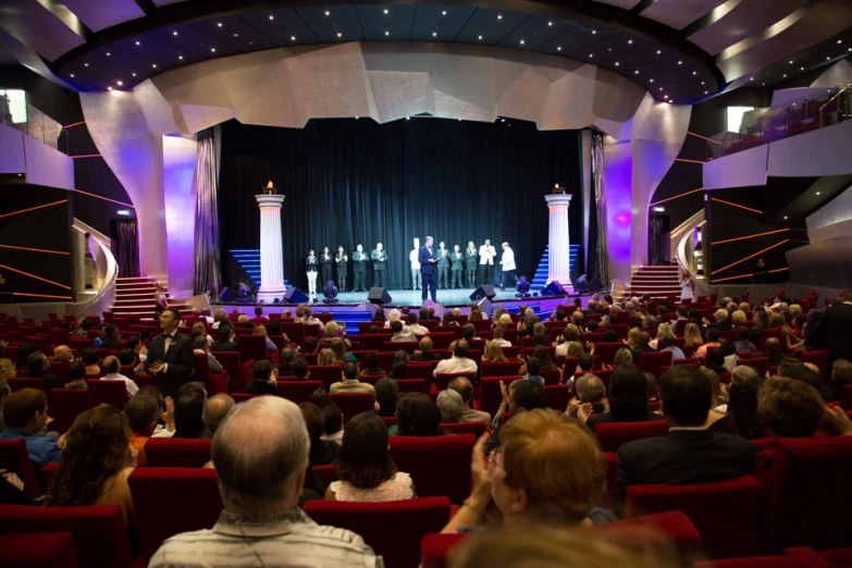 an audience in seats at an event in front of an curtain