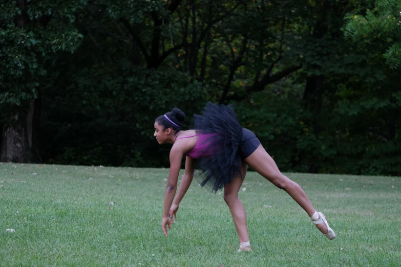 a woman doing a ballet pose in the grass