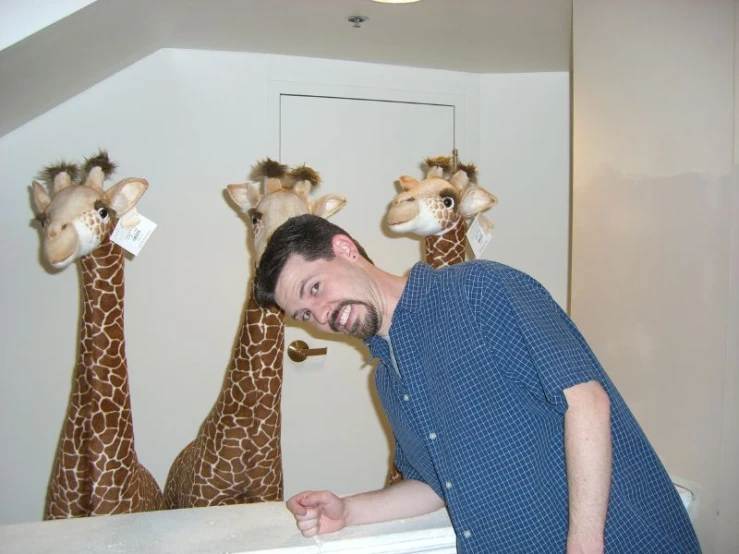 man making a funny face while standing behind giraffe head stuffed animal