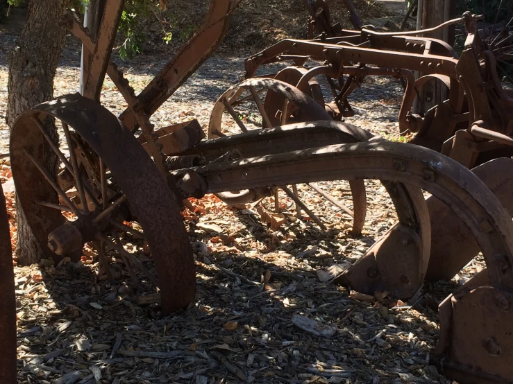 several antique wooden machines stand on a dirt area