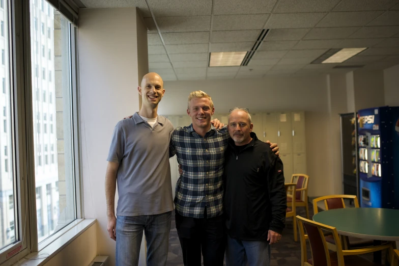 three men standing beside each other next to windows