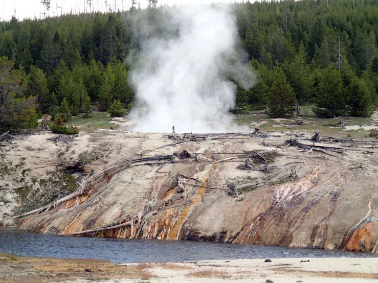 a very tall geyser near some rocks and water