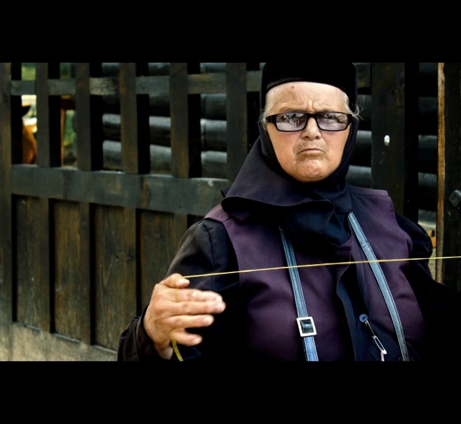 an older woman wearing glasses is holding a small piece of clothing