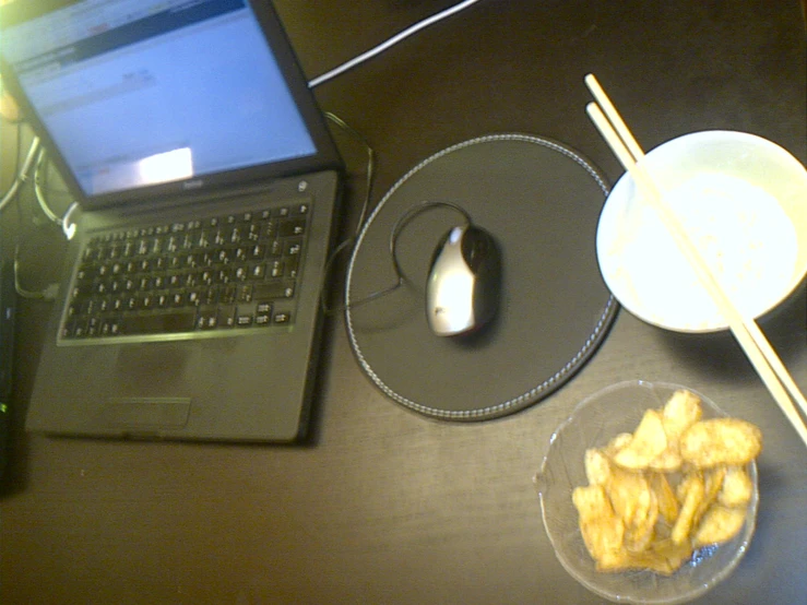 two cups and a plate of food with one of the plates and the computer mouse sitting on the desk