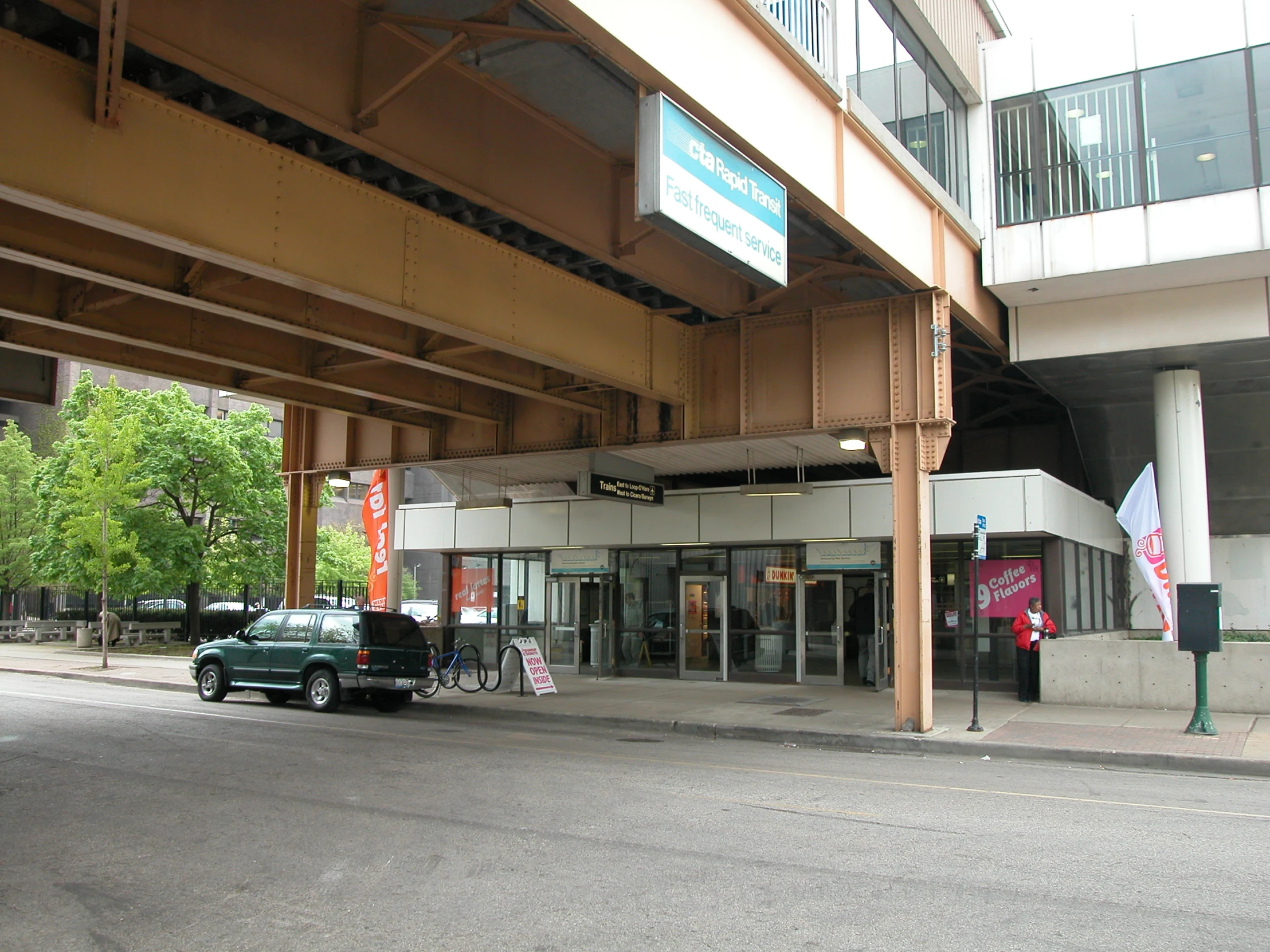 two cars parked under an overpass on a city street