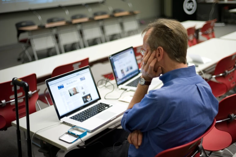 man in front of two laptops with one on their side