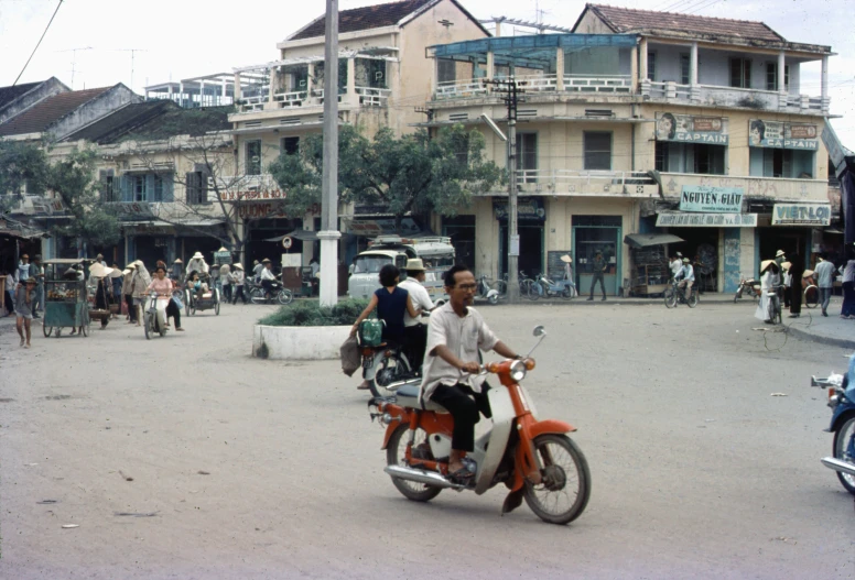 a man driving a motor scooter through a busy street